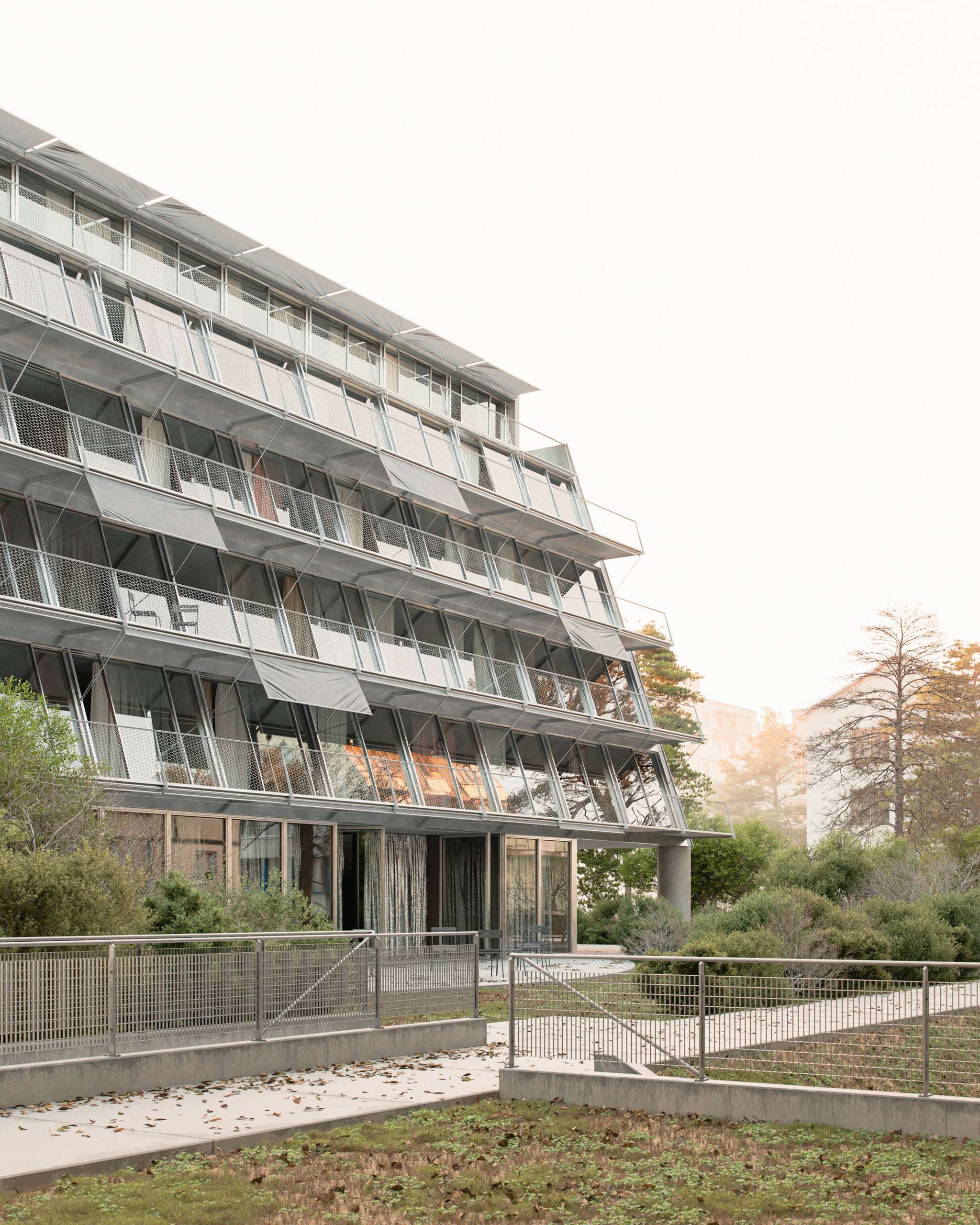 3D rendering of a housing block with deep balconies facing a landscaped courtyard